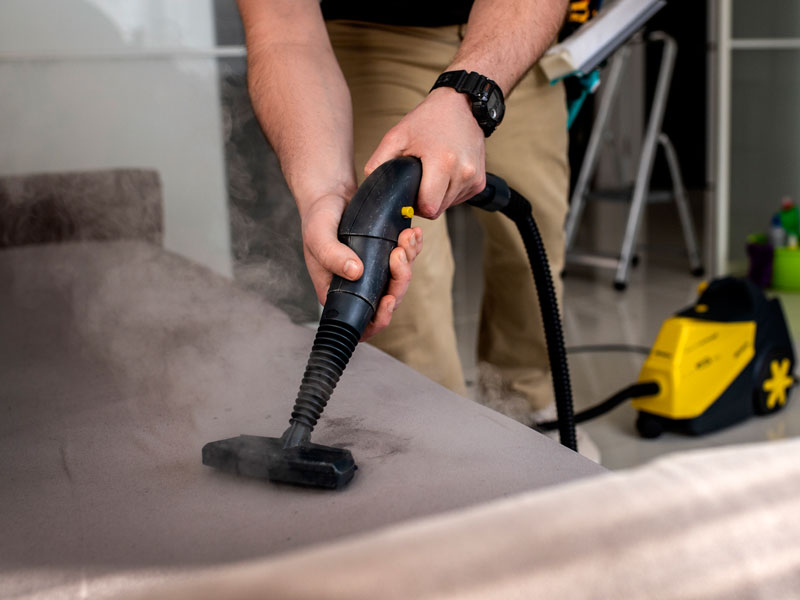 A Cleaner cleaning  sofa using vacuum cleaner