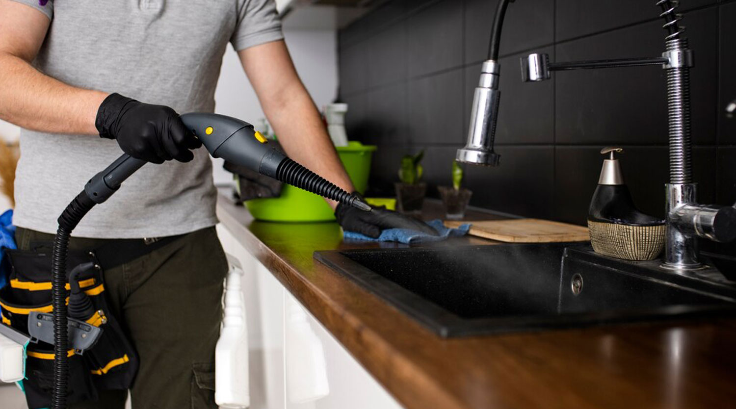 A  male cleaner cleaning kitchen basin