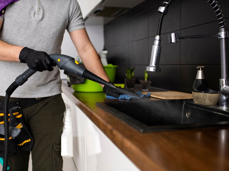 A  male cleaner cleaning kitchen basin